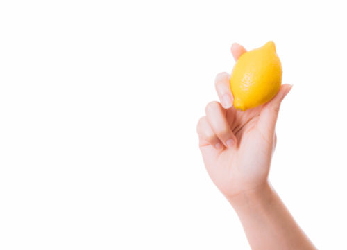 揚げ物にかけると老化物質を抑制してくれるレモンを持っている人の手